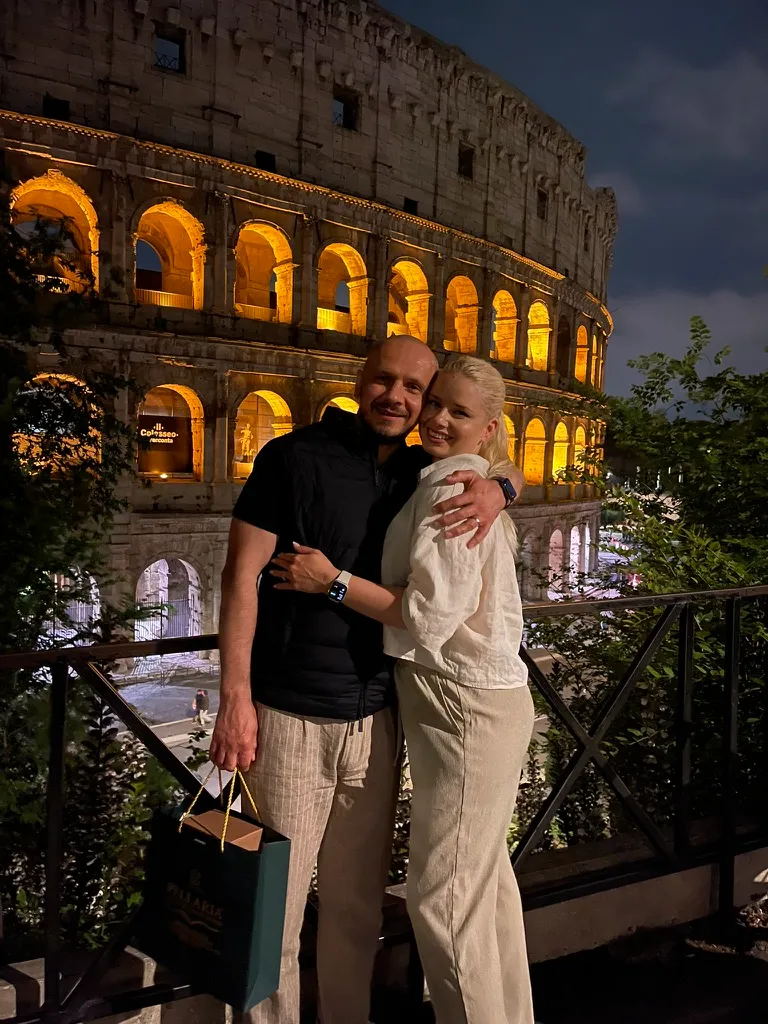 Couple at the Colosseum Rome by night - golden lights illuminating the ancient amphitheatre