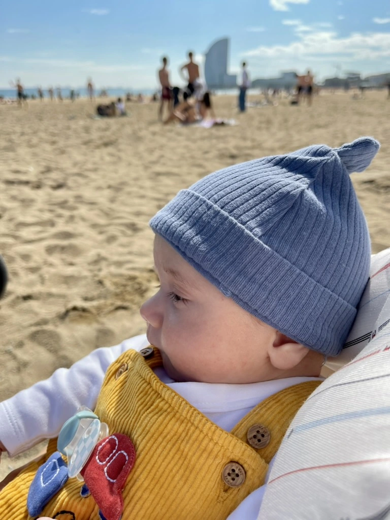 Baby on the beach in Barcelona during first family vacation, part of a family travel blog post.
