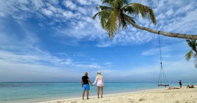 Couple walking on a white-sand beach on a Maldives local island — turquoise water and tropical scenery.